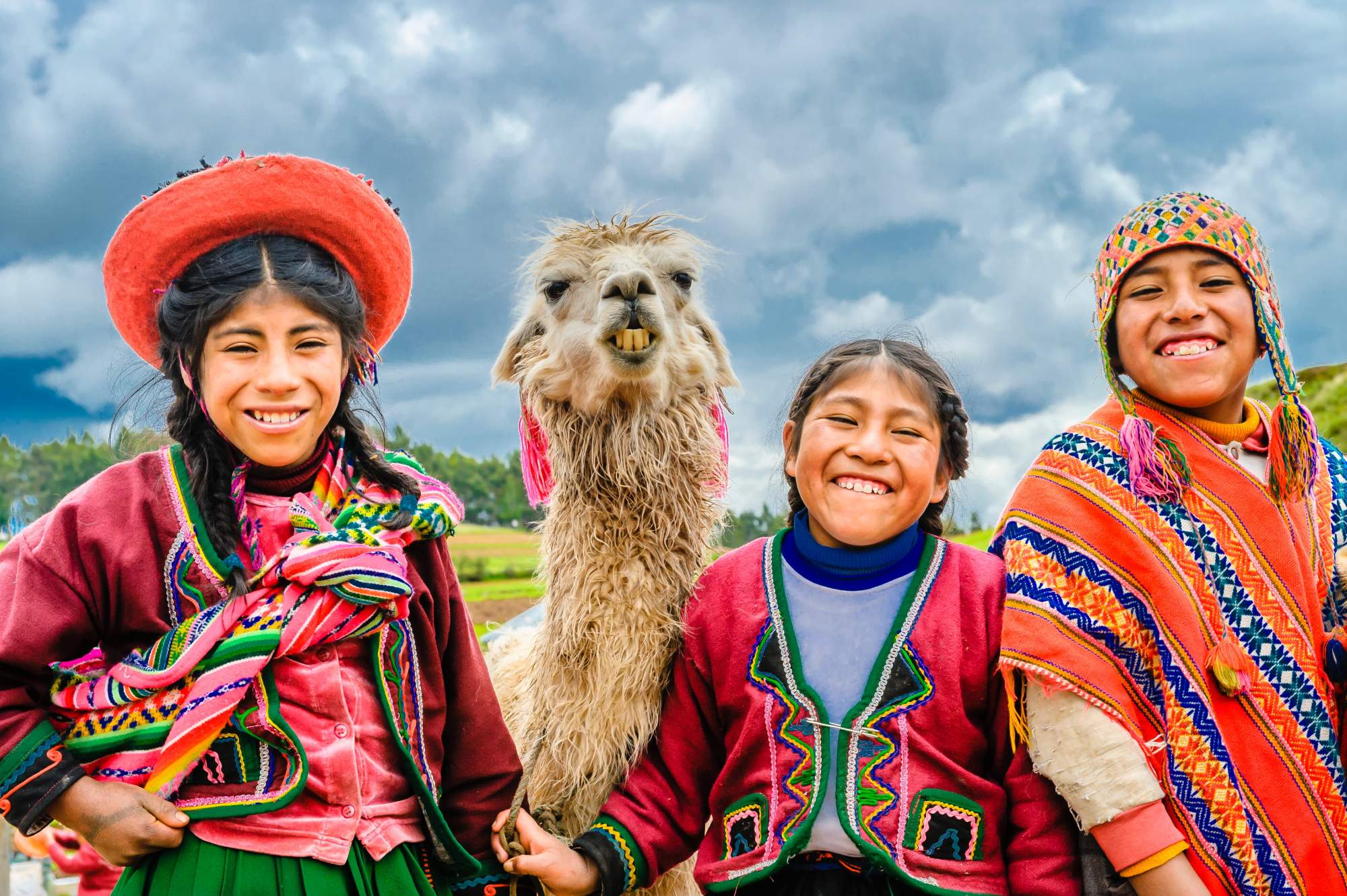 Peruvian children in traditional dress with llamas in the Sacred Valley